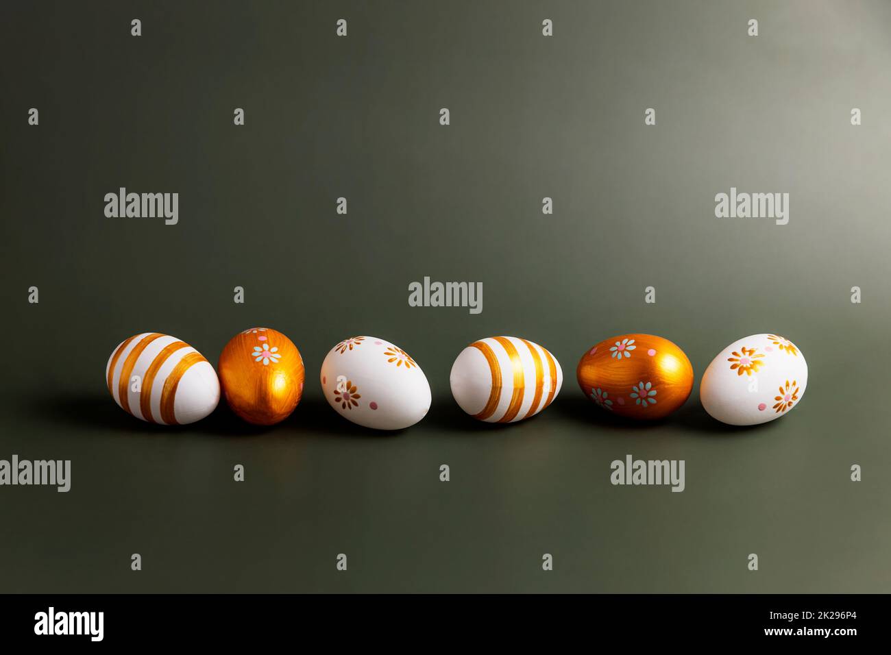 Easter holiday conceptual background. Painted golden Easter eggs on green table Stock Photo