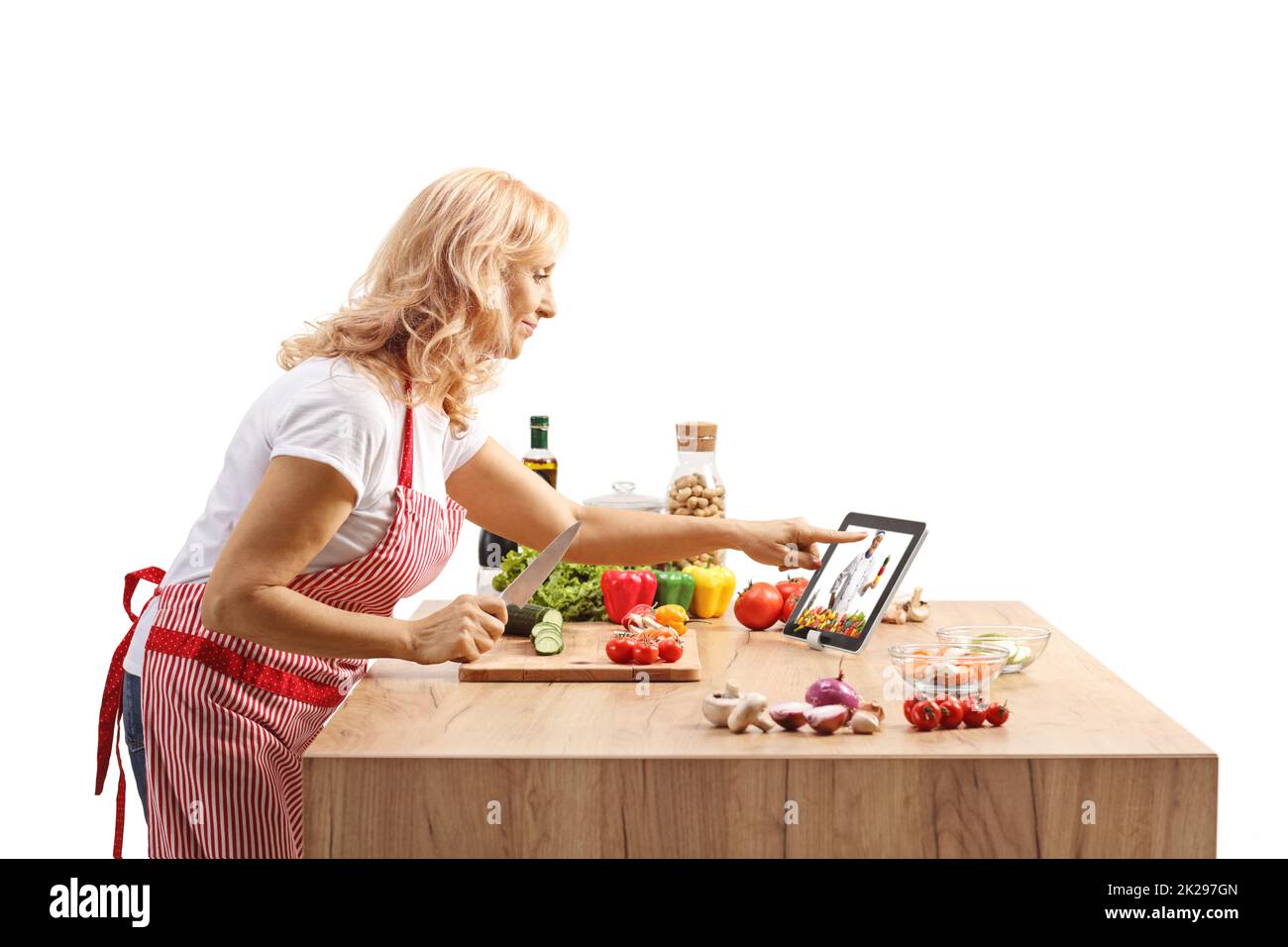 Mature woman cooking on a counter and watching a video on a digital tablet Stock Photo
