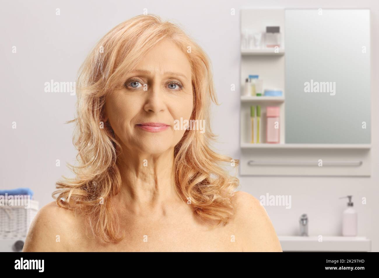 Portrait of a mature woman with blue eyes and bare shoulders inside a bathroom Stock Photo