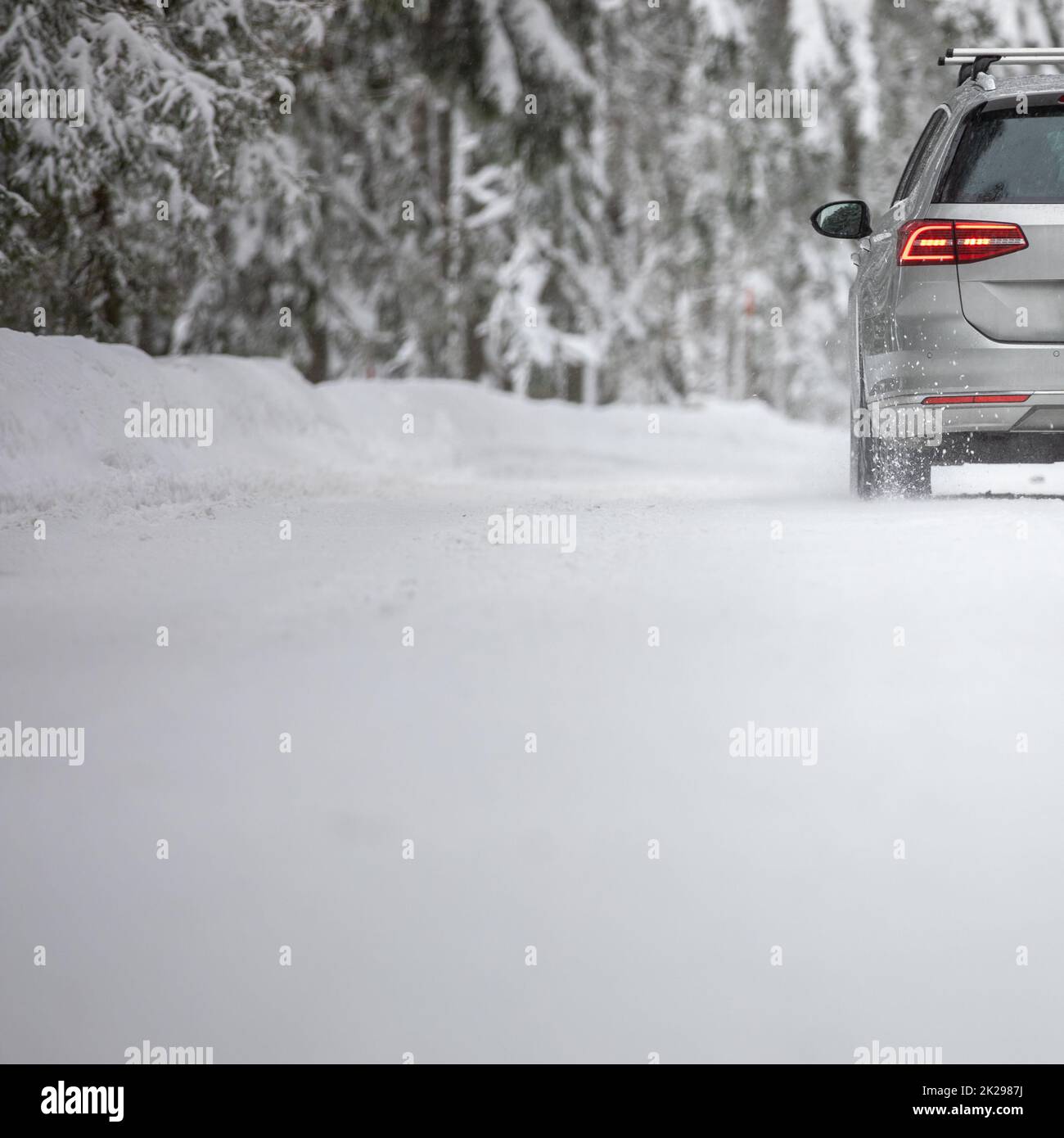 Car on a snowy winter road amid forests using its four wheel drive