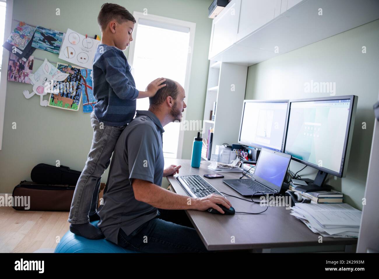 Man working on computer with son distracting him Stock Photo
