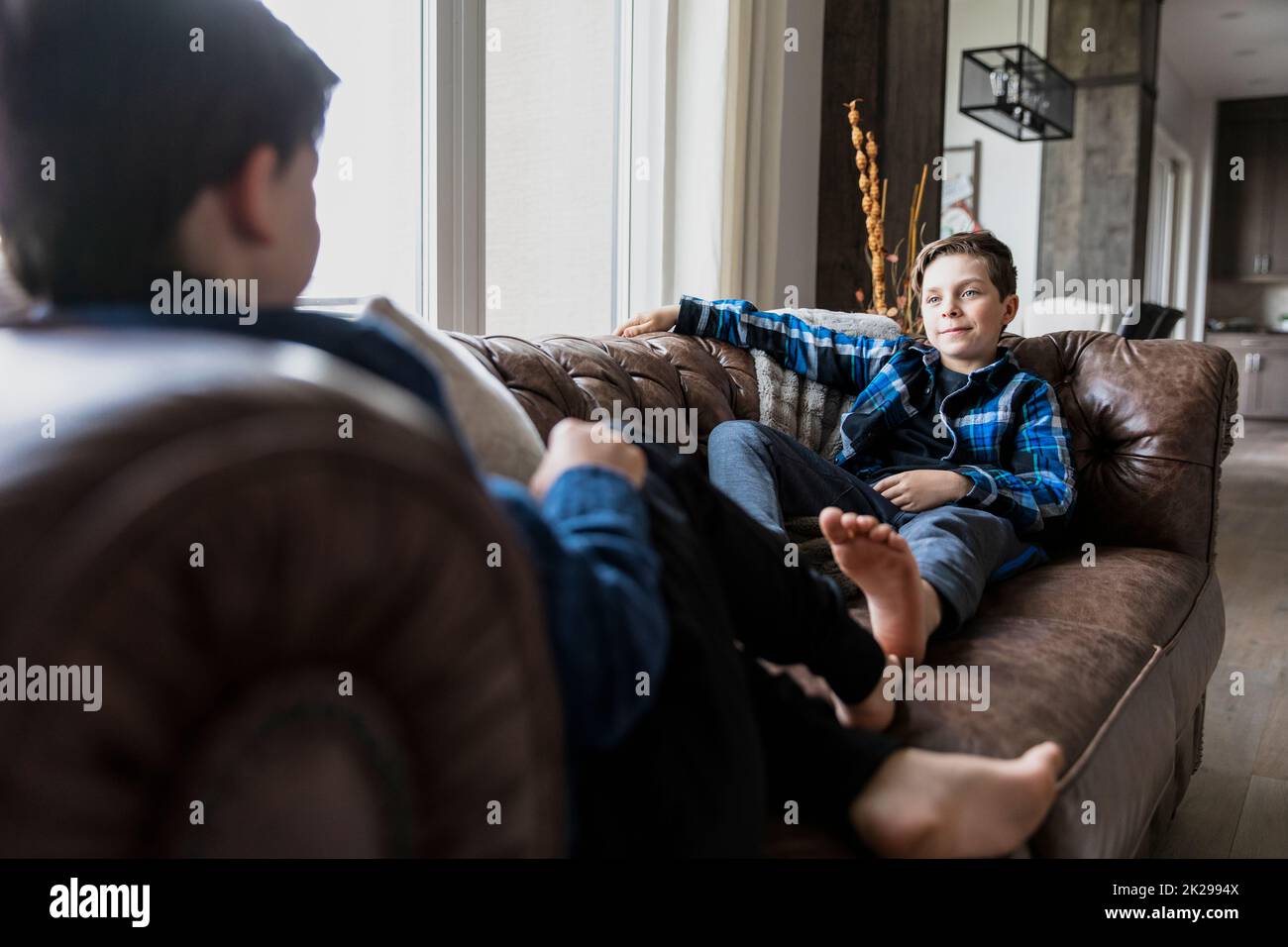 Brothers sitting on sofa looking at each other Stock Photo
