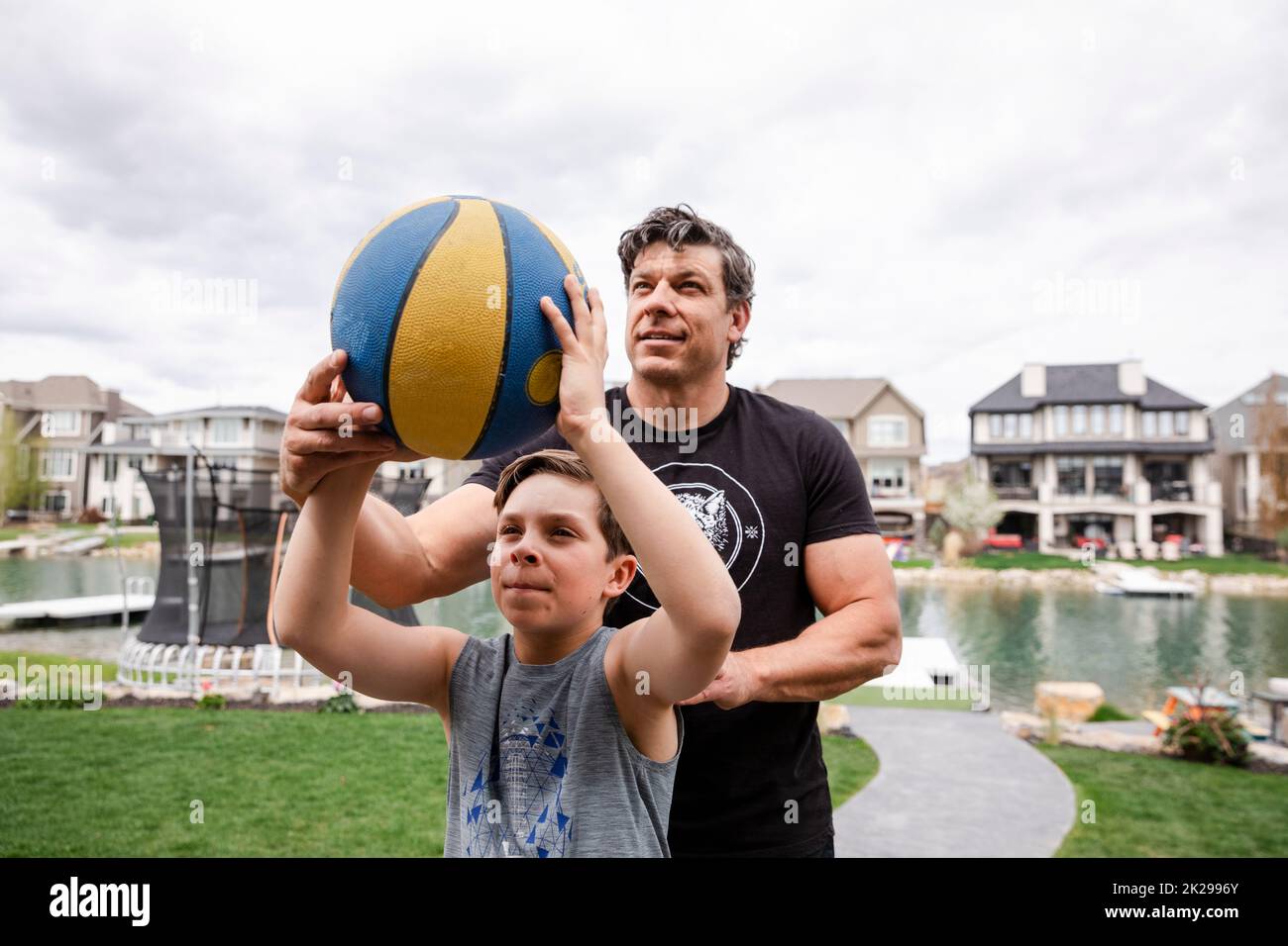 Father teaching son to aim at basketball Stock Photo