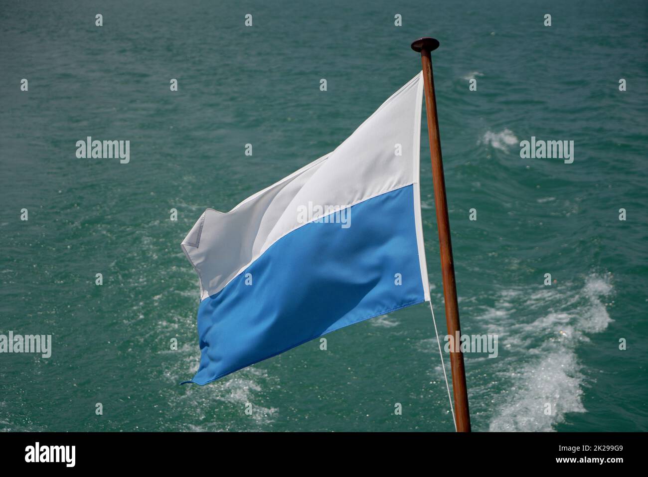 flag flies against a blue white sky on a summer day in Bavaria Stock Photo