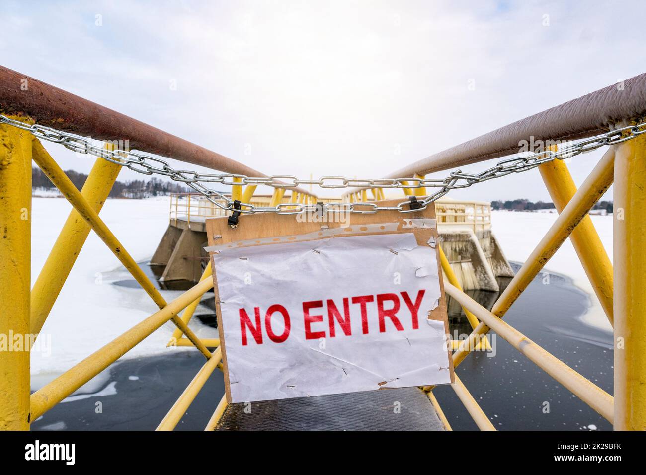 No entry sign on chain in front of yellow metallic bridge Stock Photo