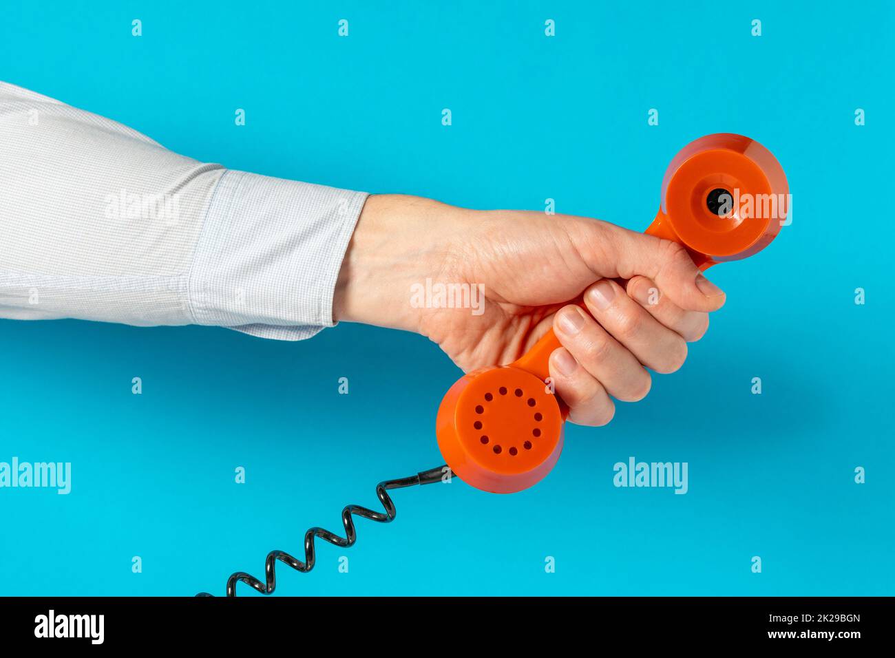 Old telephone receiver in hand over blue background Stock Photo