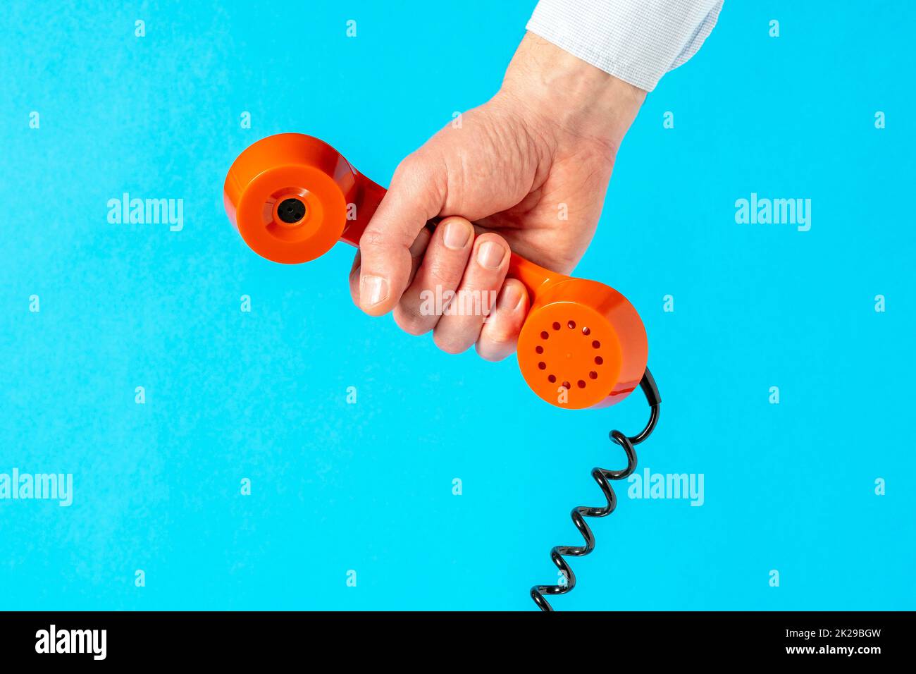 Hand holding old telephone receiver over blue background Stock Photo