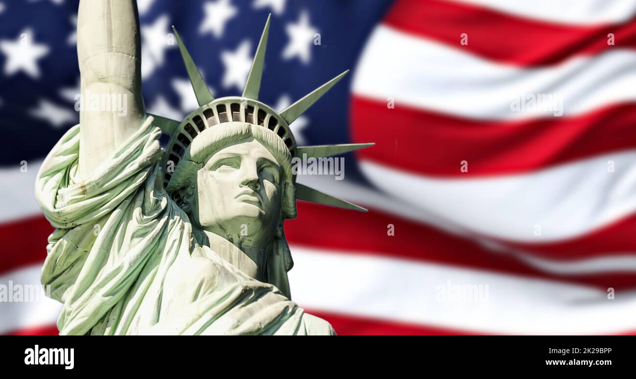 the statue of liberty with blurred american flag waving in the background Stock Photo