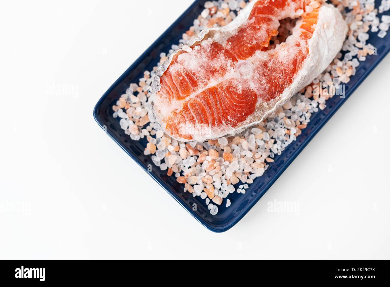 Grilled fresh raw salmon steak with large coarse pink salt. Healthy