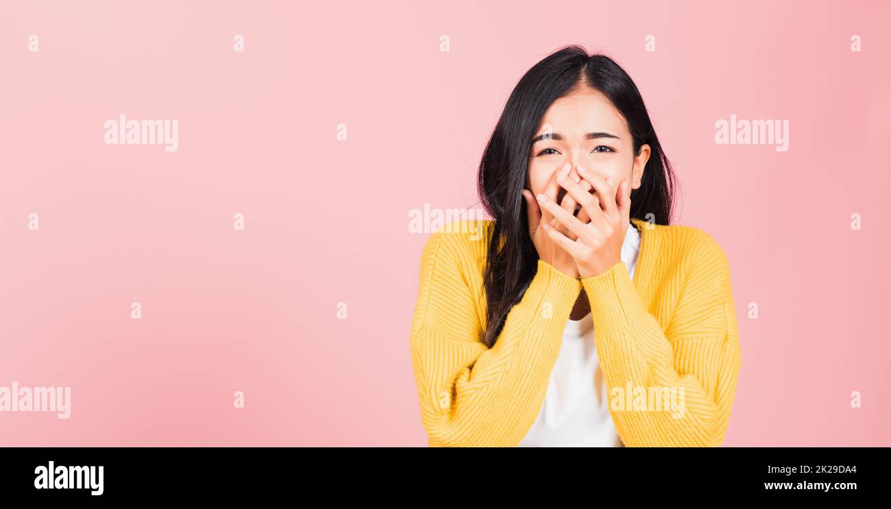 Asian portrait beautiful cute young woman standing amazed, shocked afraid mouth covered gesturing hand palms looking camera, studio shot isolated on pink background, Thai female scared with copy space Stock Photo