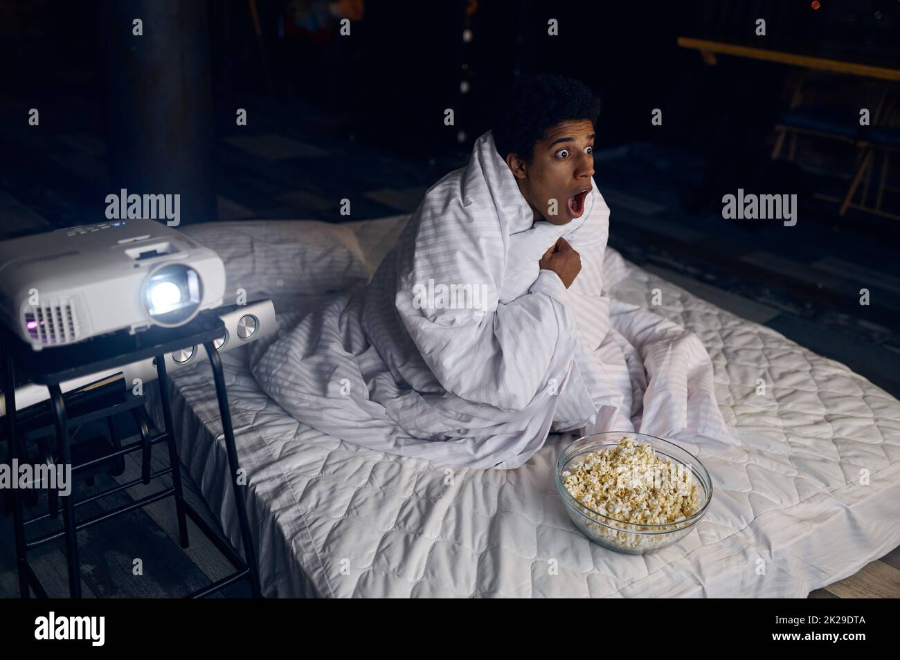 Funny guy watching horror hiding under blanket Stock Photo Alamy
