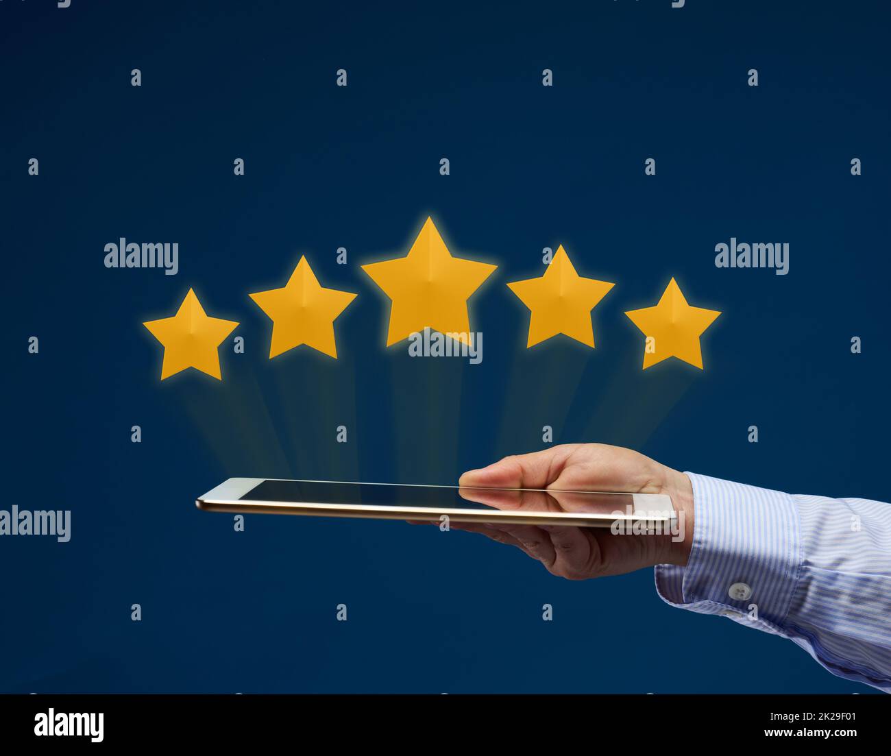 a female hand holds an electronic tablet and five yellow virtual stars above the screen. User rating of the application, service. Quality Rating Stock Photo