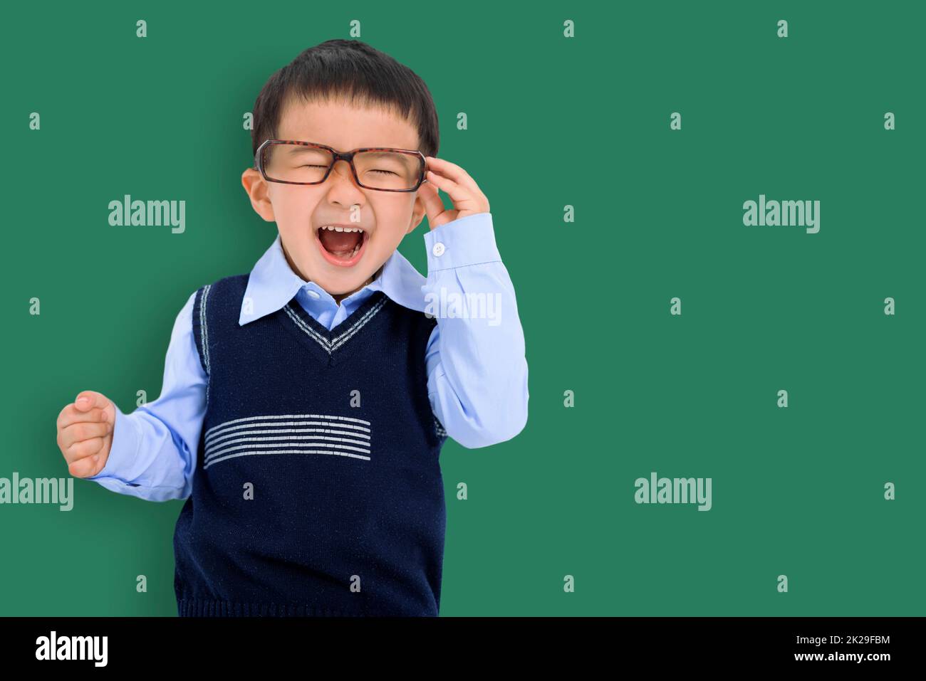Happy Kid boy holding glasses and having fun stand before chalkboard Stock Photo