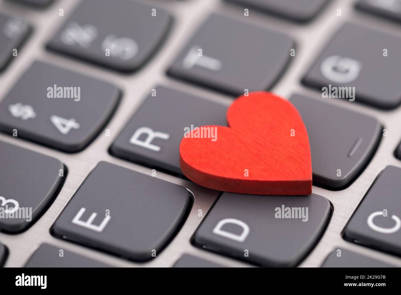 Small red heart on computer keyboard. Internet dating concept. Stock Photo