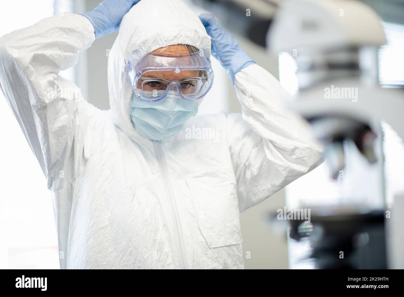 Medical researcher putting on full protective equipment in laboratory ...
