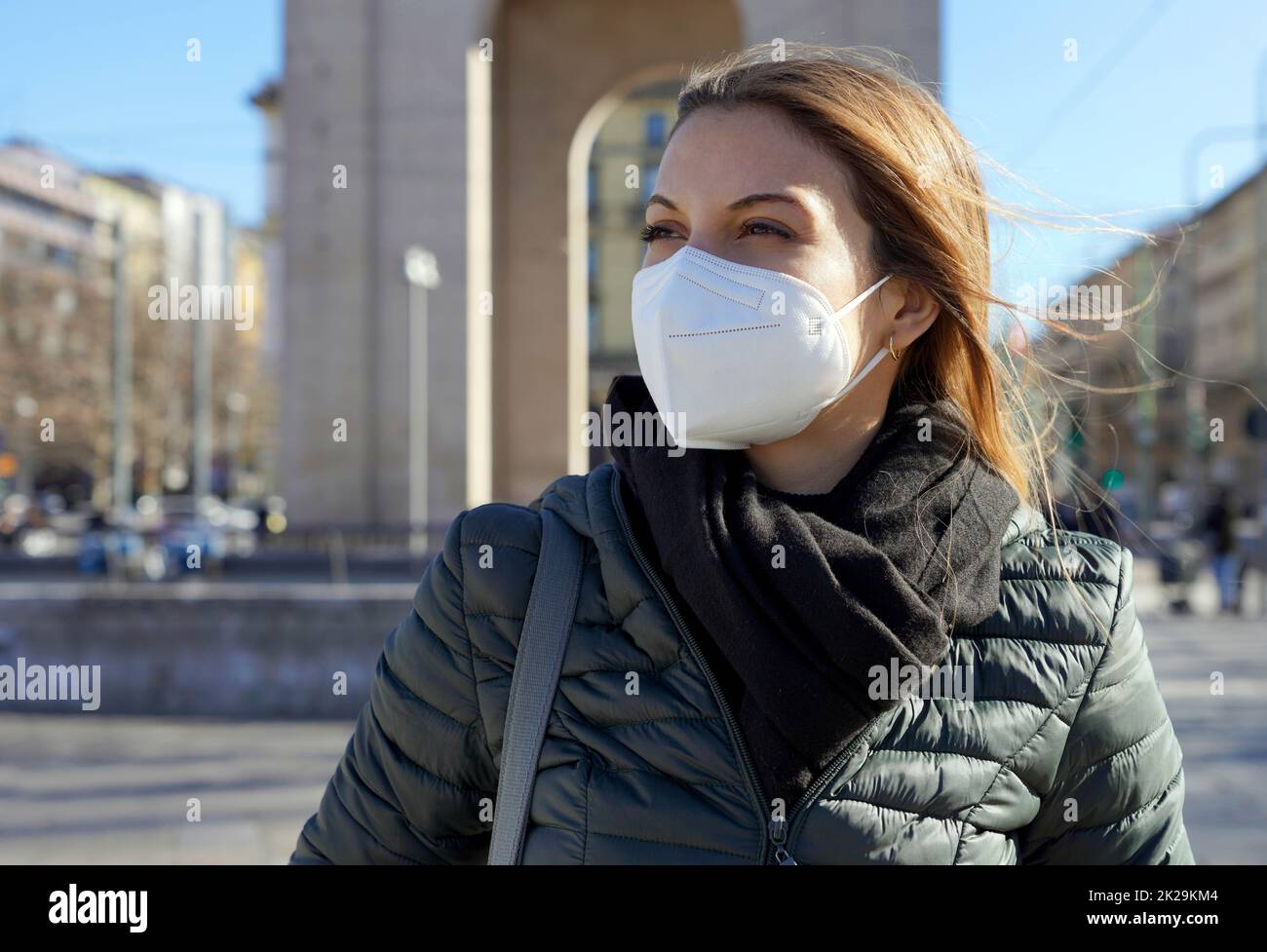 Beautiful woman in city street wearing KN95 FFP2 mask protective against respiratory disease looking to the side Stock Photo