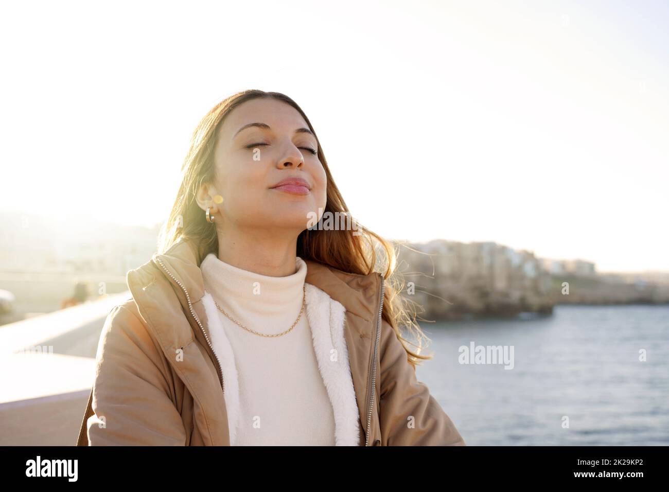 Portrait of young charming woman breathing fresh air relaxing with closed eyes on the beach Stock Photo