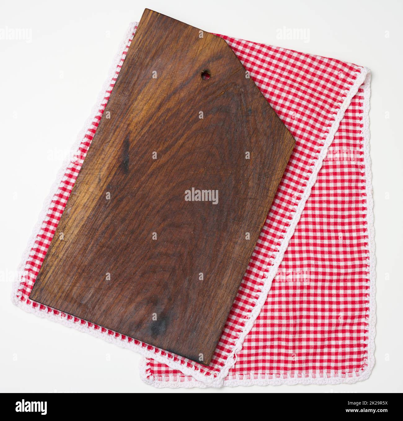 empty rectangular wooden kitchen cutting board and red towel in a white cage on a white table, top view Stock Photo