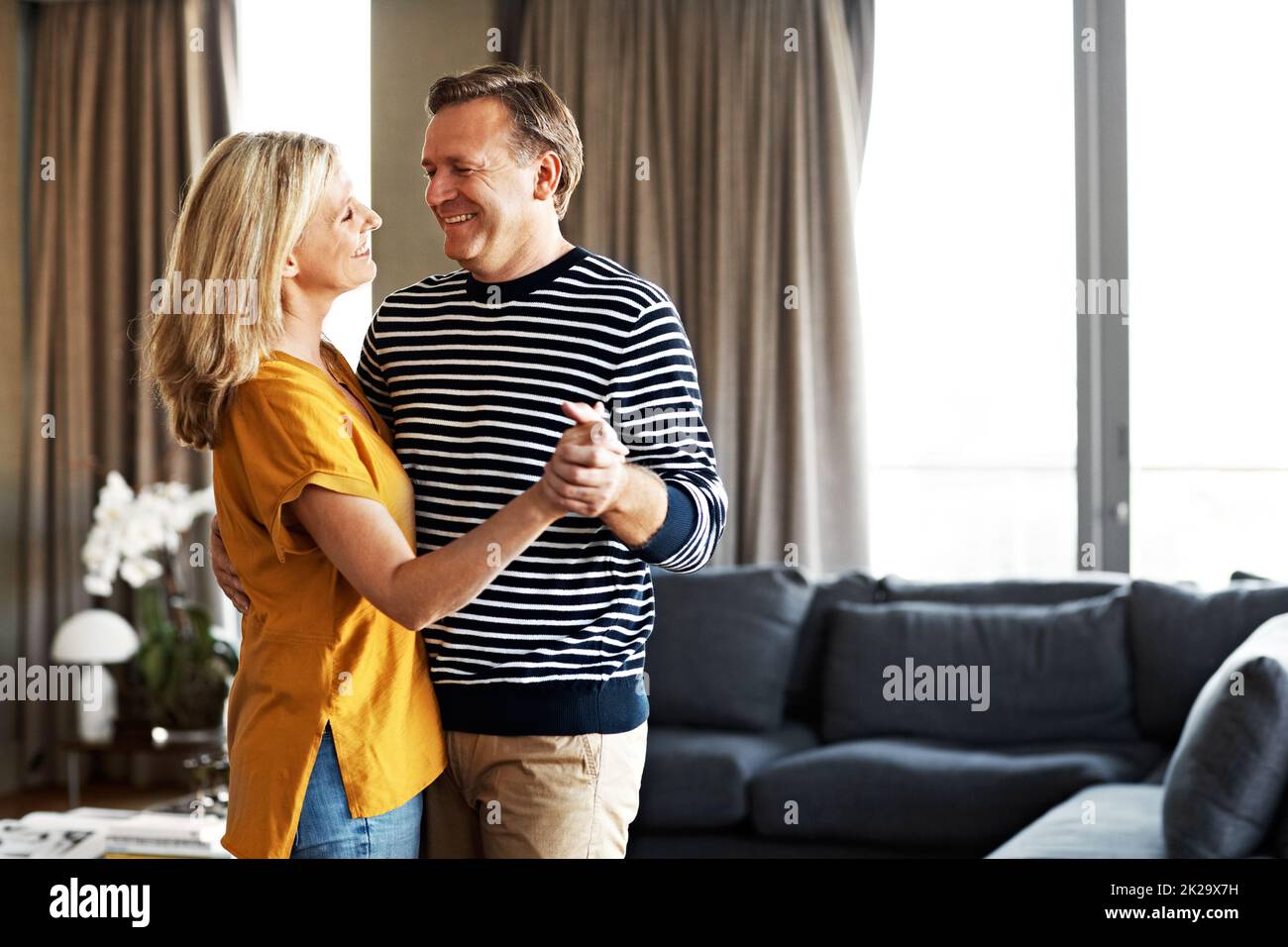Dancing in the living room. Shot of an affectionate mature couple dancing in their living room. Stock Photo