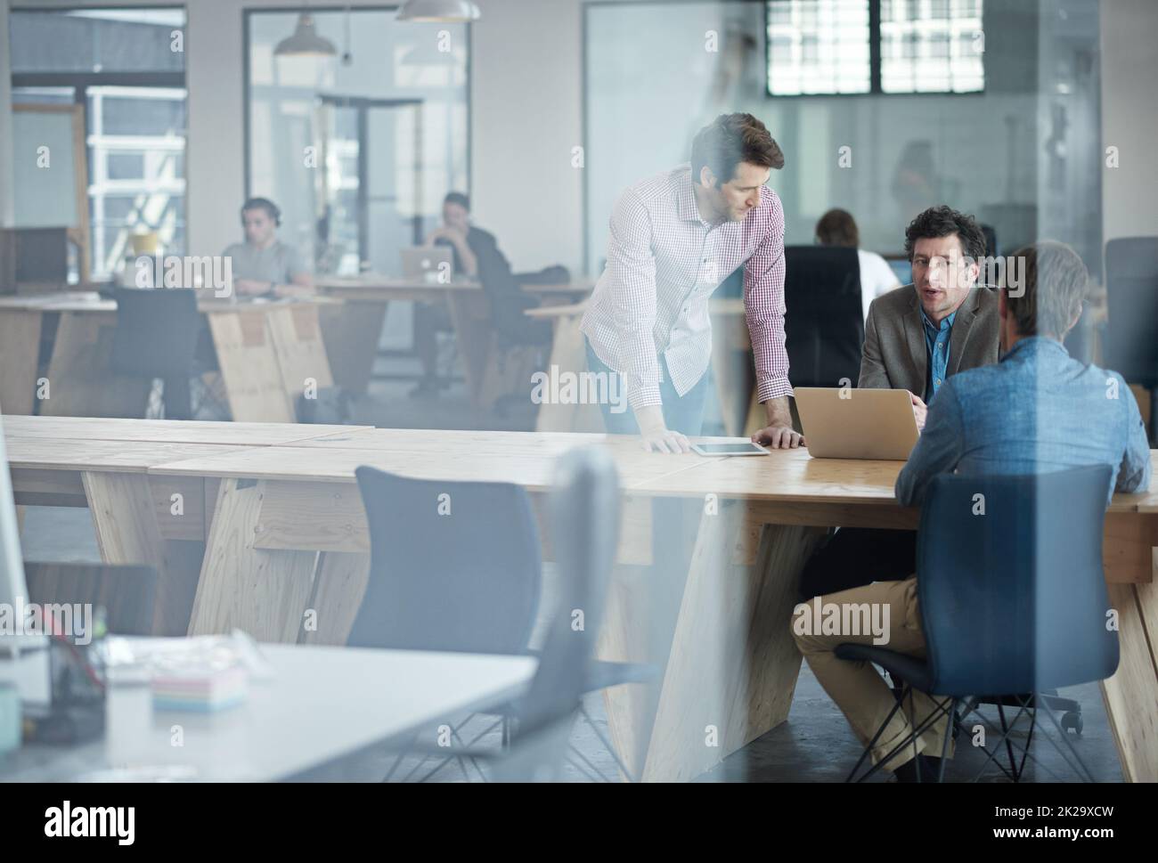 Sharing ideas. Through the glass shot of a group of colleagues working together in an office. Stock Photo