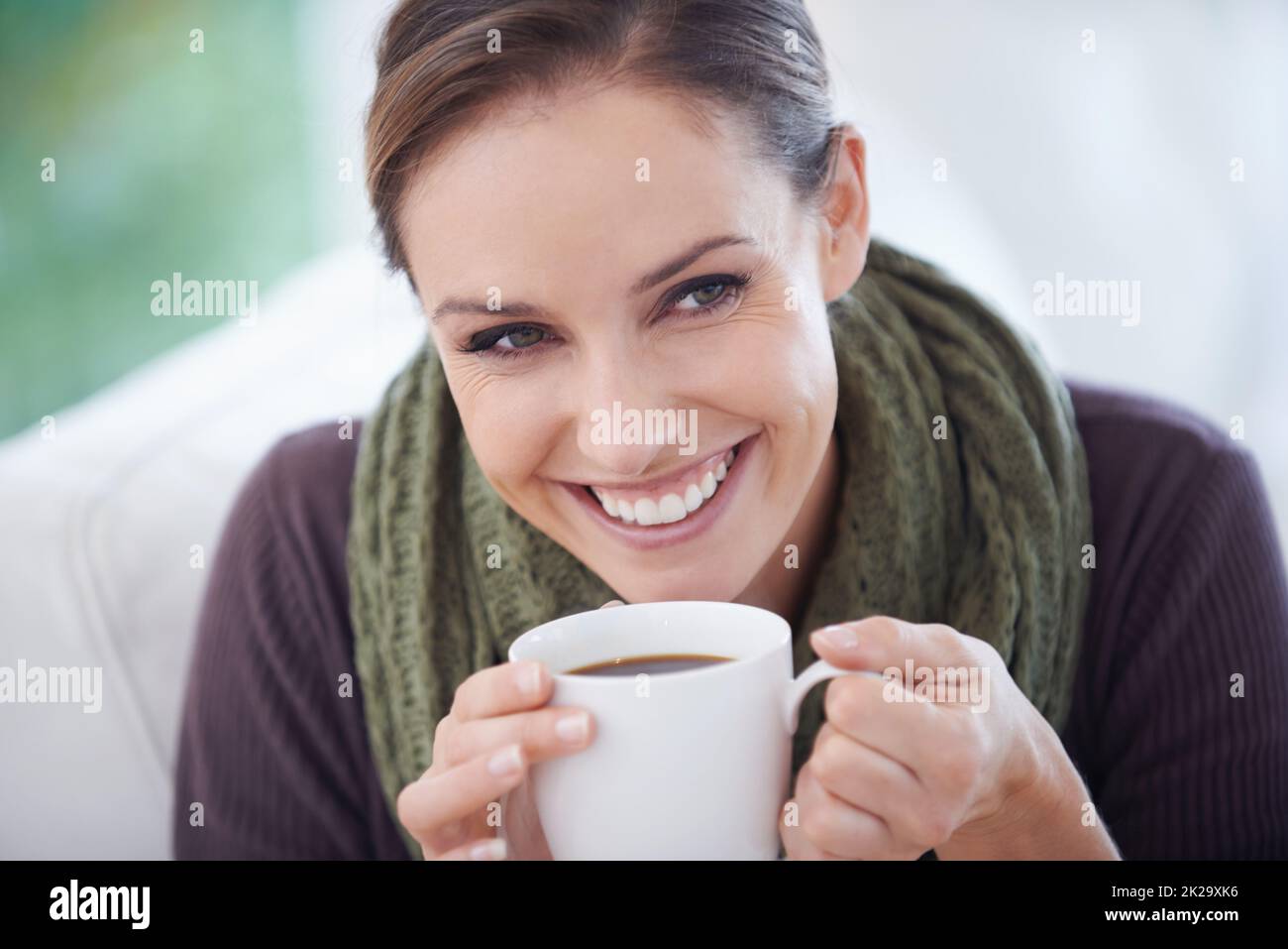 Enjoying the fresh aroma. A young woman smiling happily while holding a cup of coffee - closeup. Stock Photo