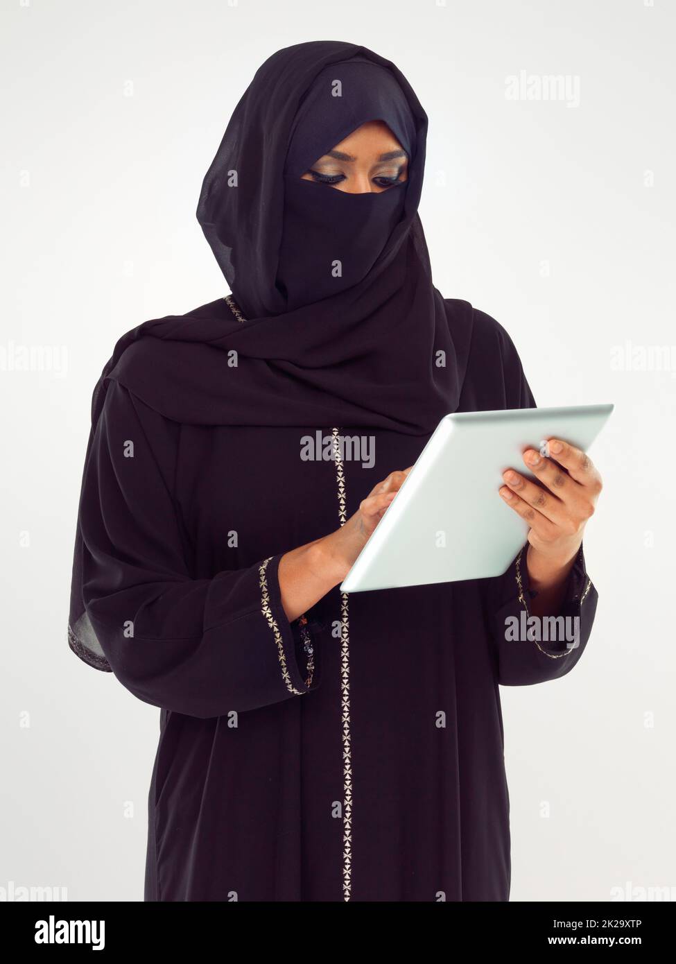 Focused on her emails. Studio shot of a woman in a burqa using a digital tablet. Stock Photo