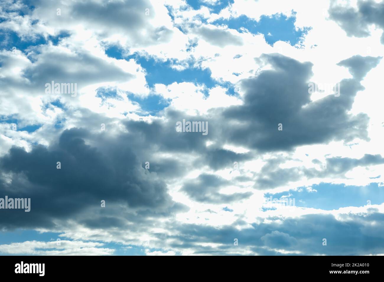 Blue sky with thunderclouds. The sun breaks through the clouds. Black clouds. Stock Photo