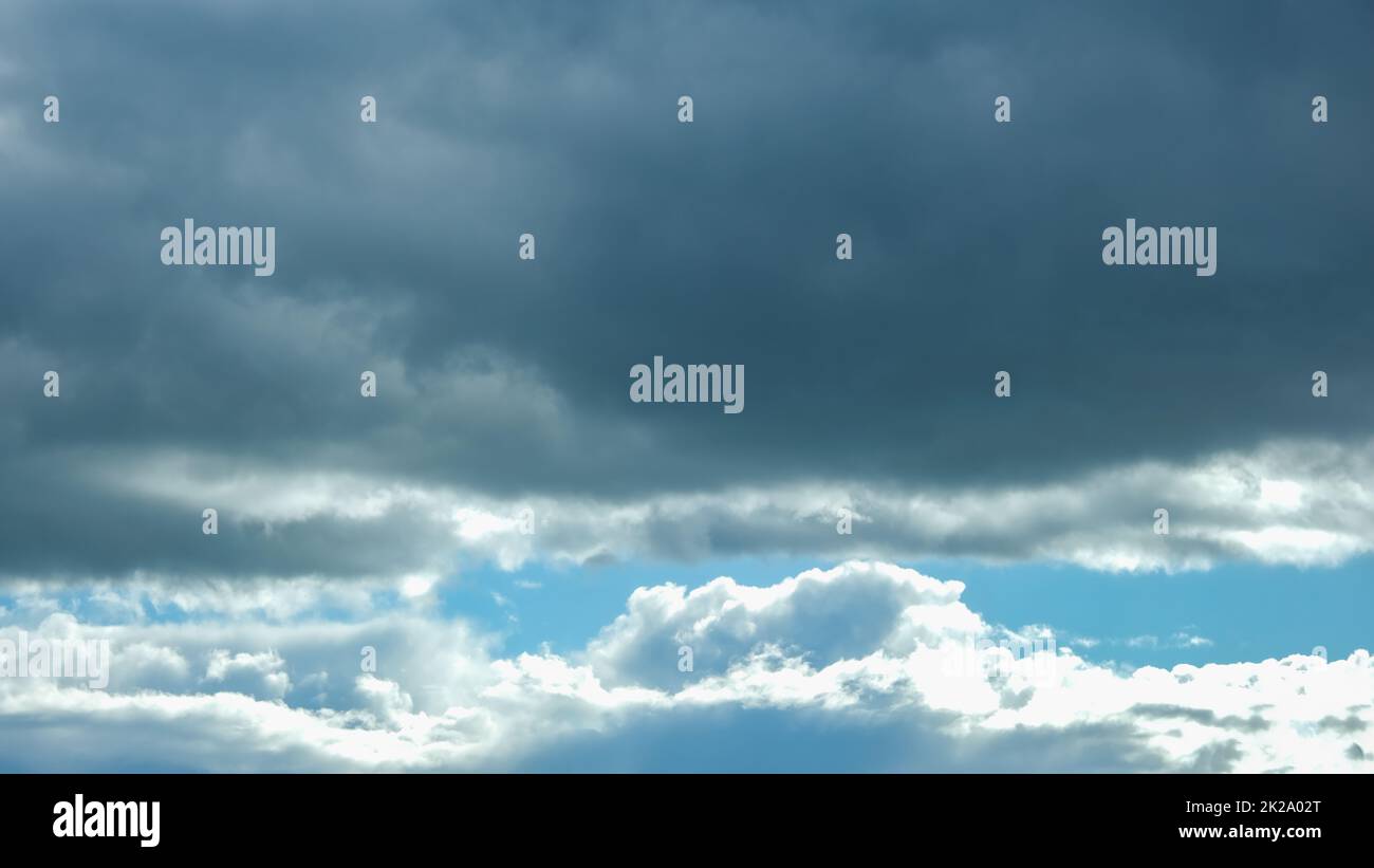 Blue sky with thunderclouds. The sun breaks through the clouds. Black clouds. Banner. Stock Photo
