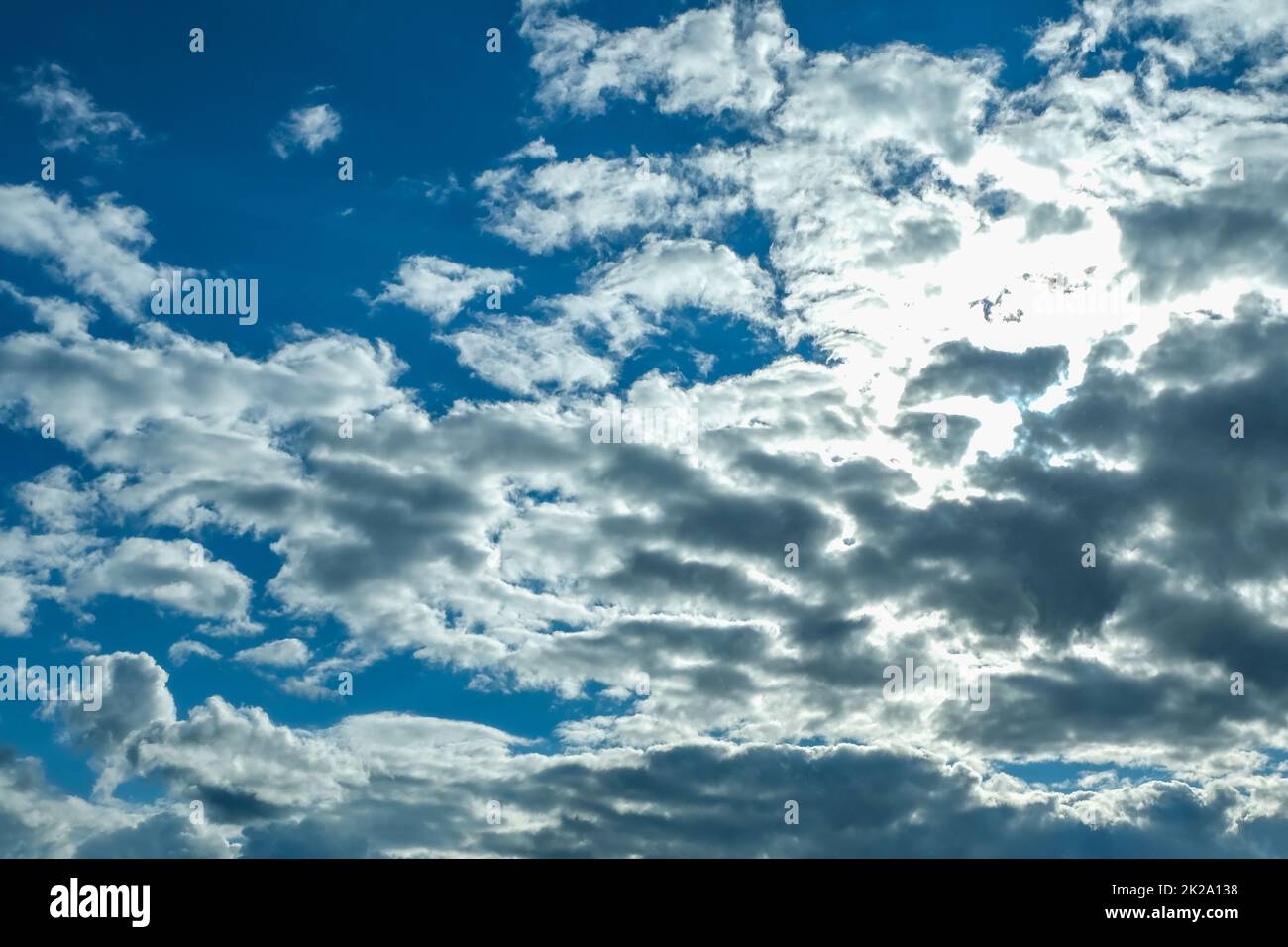 Blue sky with thunderclouds. The sun breaks through the clouds. Black clouds. Stock Photo