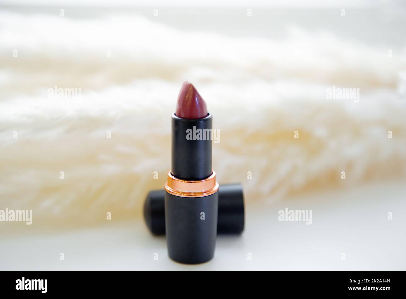 Open red lipstick stands on the background of fluffy reeds on a white background Stock Photo