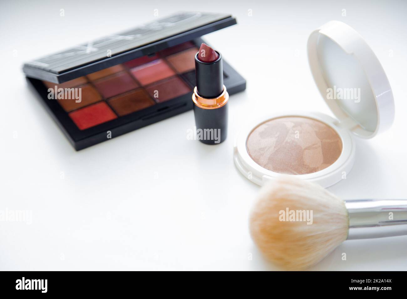 The white face powder and bronzer, black packaging with eye shadow, lipstick and brush lying on white background Stock Photo