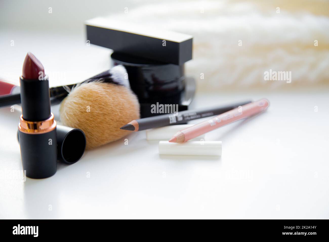 Two pencils for eyes and lips, lipstick, brushes, blush lie together on white background Stock Photo