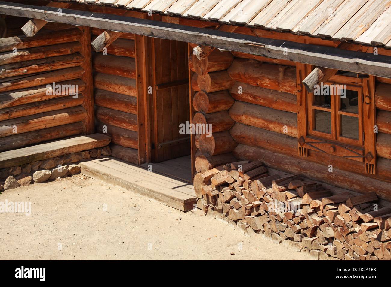 Wooden log cabin, lit by sun, detail on entrance door. Stock Photo