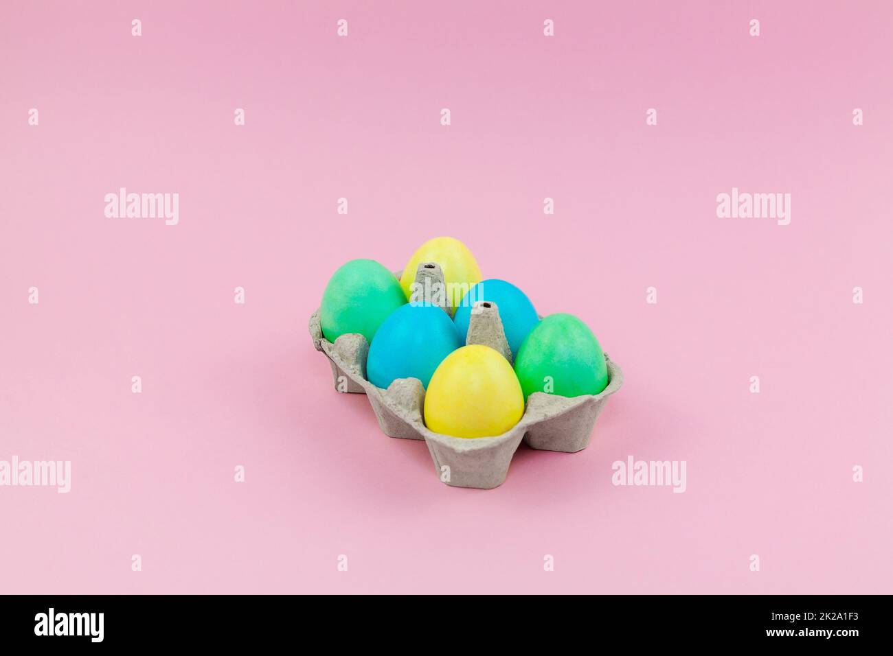 Box with colorful Easter eggs on a pink background Stock Photo