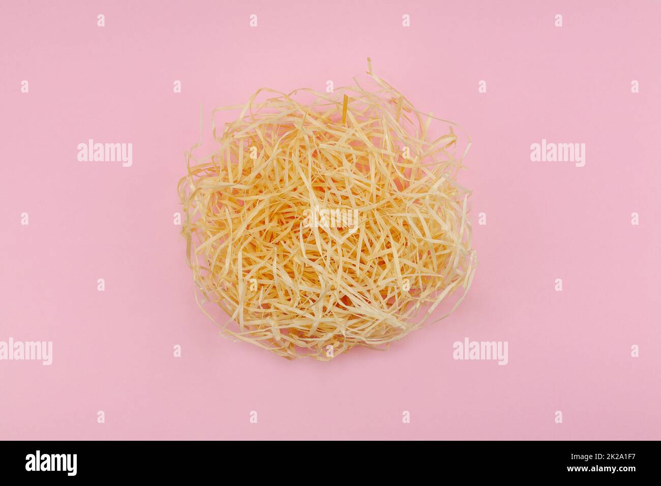 Creative flat lay concept. The love nest made of beige hay and one red heart is a symbol of love and the growth of love. Paradise pink background. Focus in the middle. Valentines or Easter idea. Stock Photo