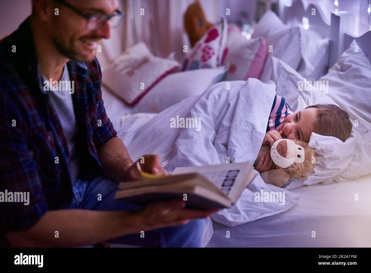 Just one more story daddy. Shot of a father reading a bedtime story to