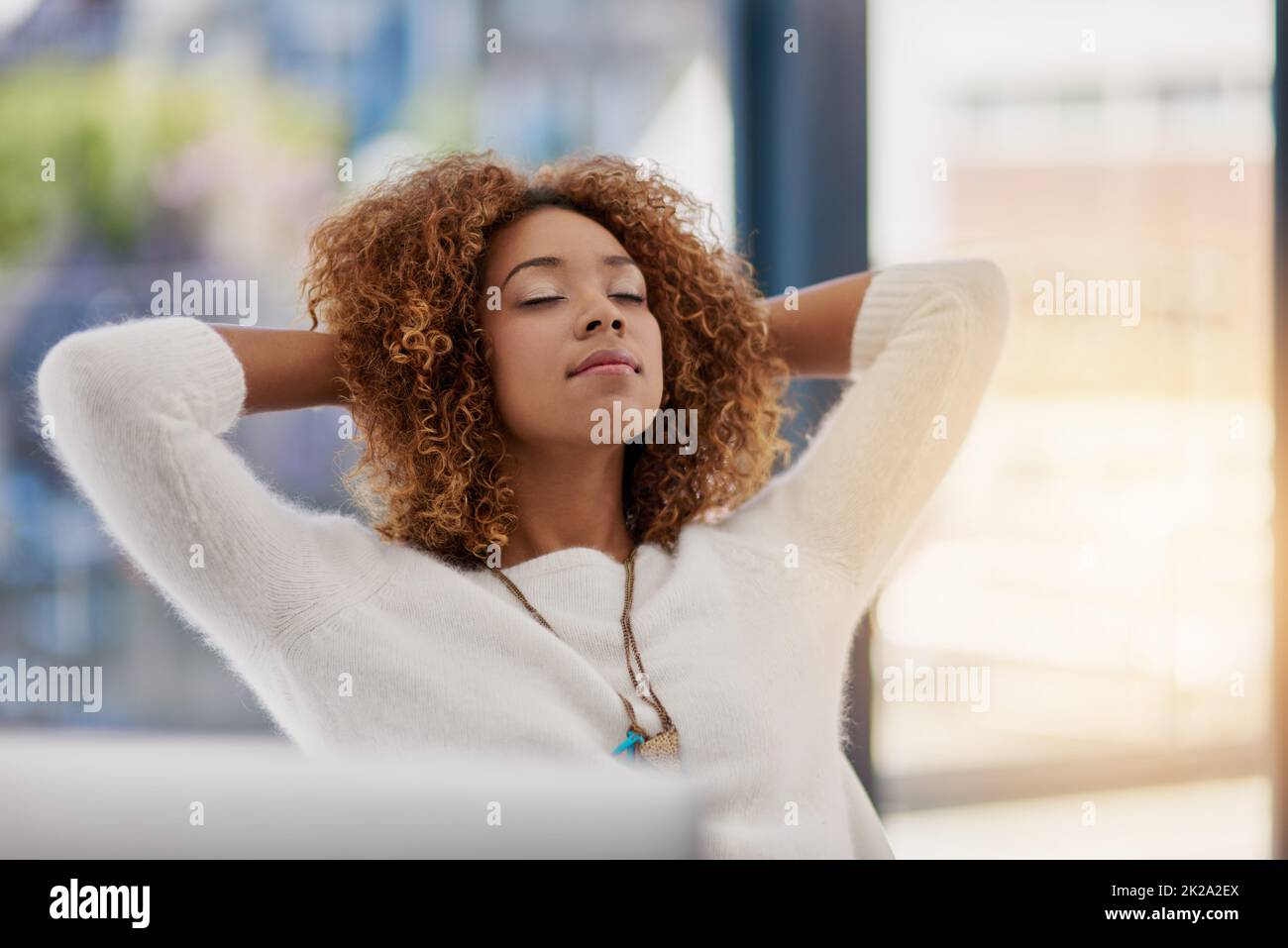 Contemplating the road to success. Shot of a young entrepreneur leaning back in her chair with her hands behind her head. Stock Photo