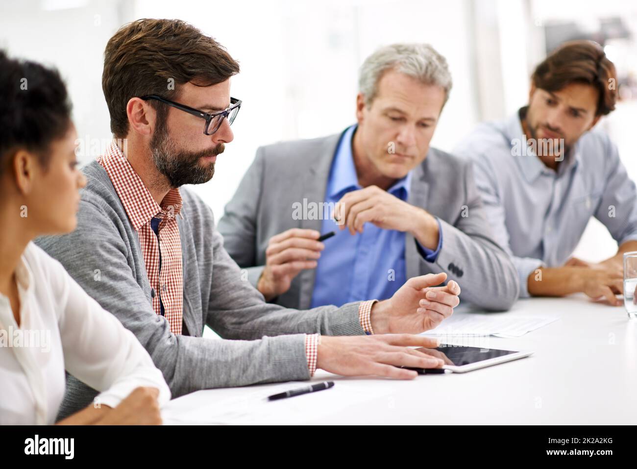 Hard working office pros. Shot of a group of young professionals working at a desk in an office. Stock Photo