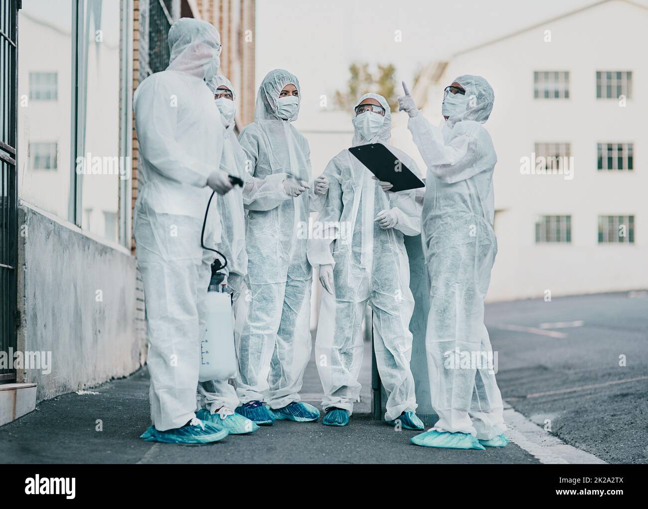 Healthcare workers are the heroes of this story. Shot of a group of healthcare workers wearing hazmat suits working together during an outbreak in the city. Stock Photo