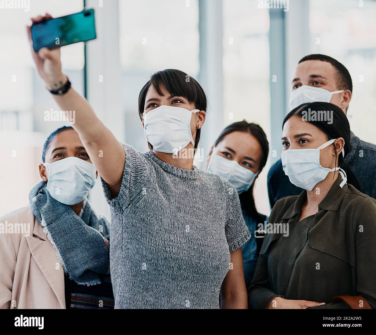 Embrace a new normal. Shot of a group of young people wearing masks and taking selfies at the airport. Stock Photo