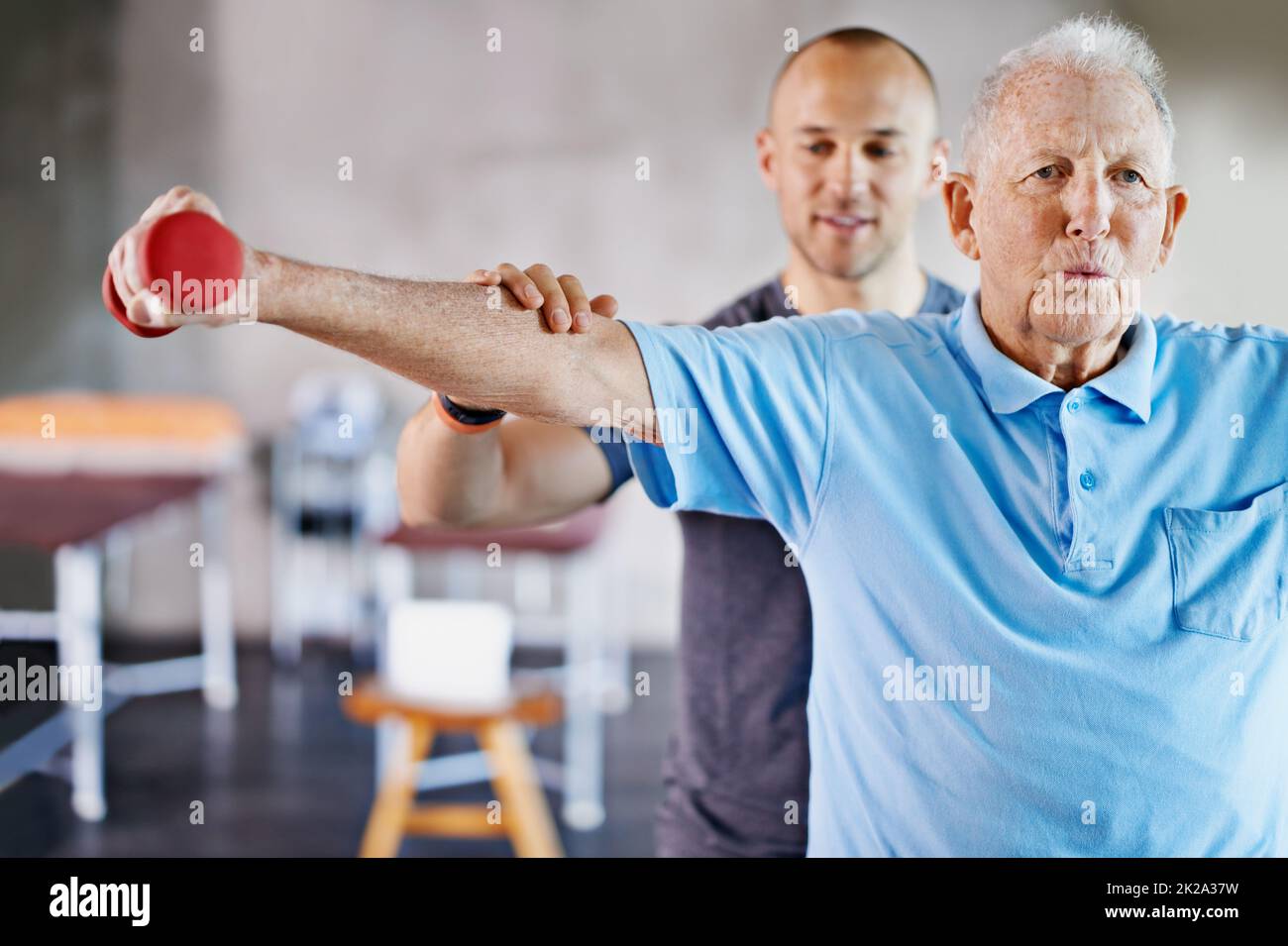Physio one lift at a time. Shot of a physiotherapist helping a senior man with weights. Stock Photo