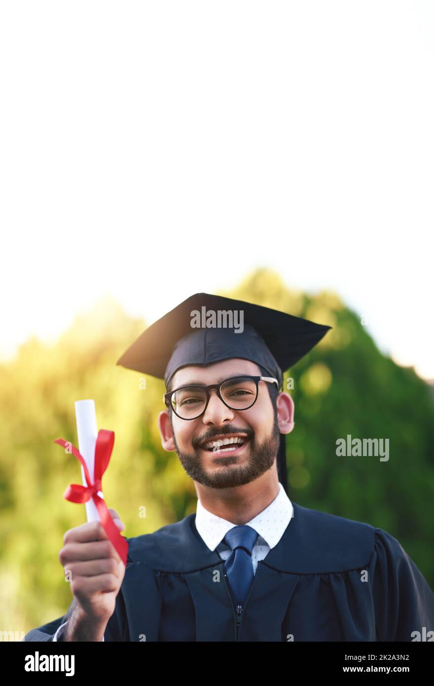 Finally, its in my hands. Portrait of a university student holding his diploma on graduation day. Stock Photo