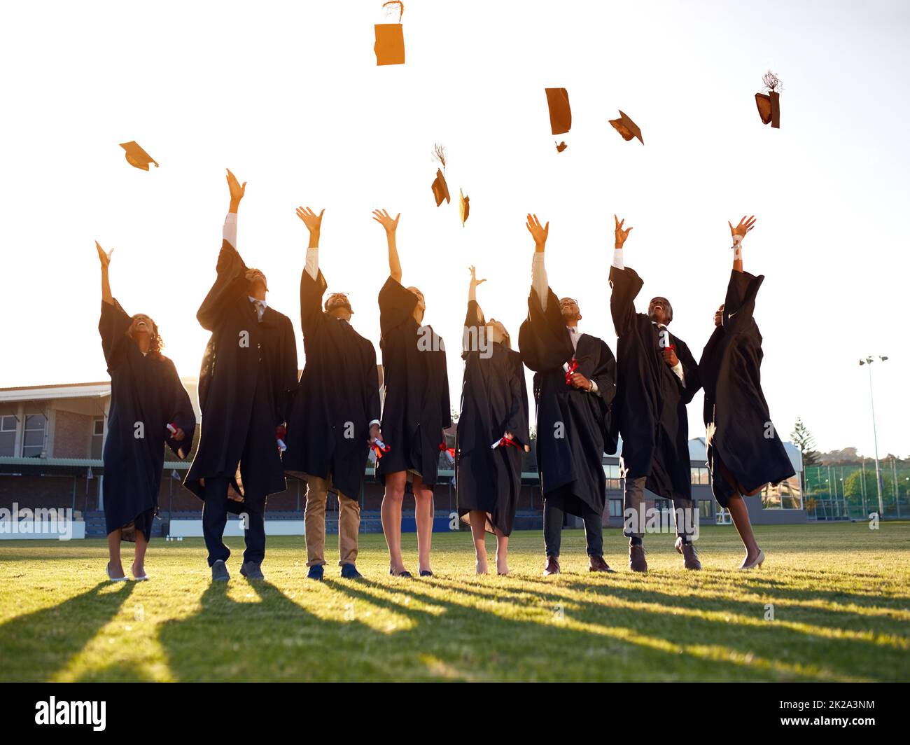 Theyve reached the end of their academic years. Shot of a group of university students throwing their hats in the air on graduation day. Stock Photo