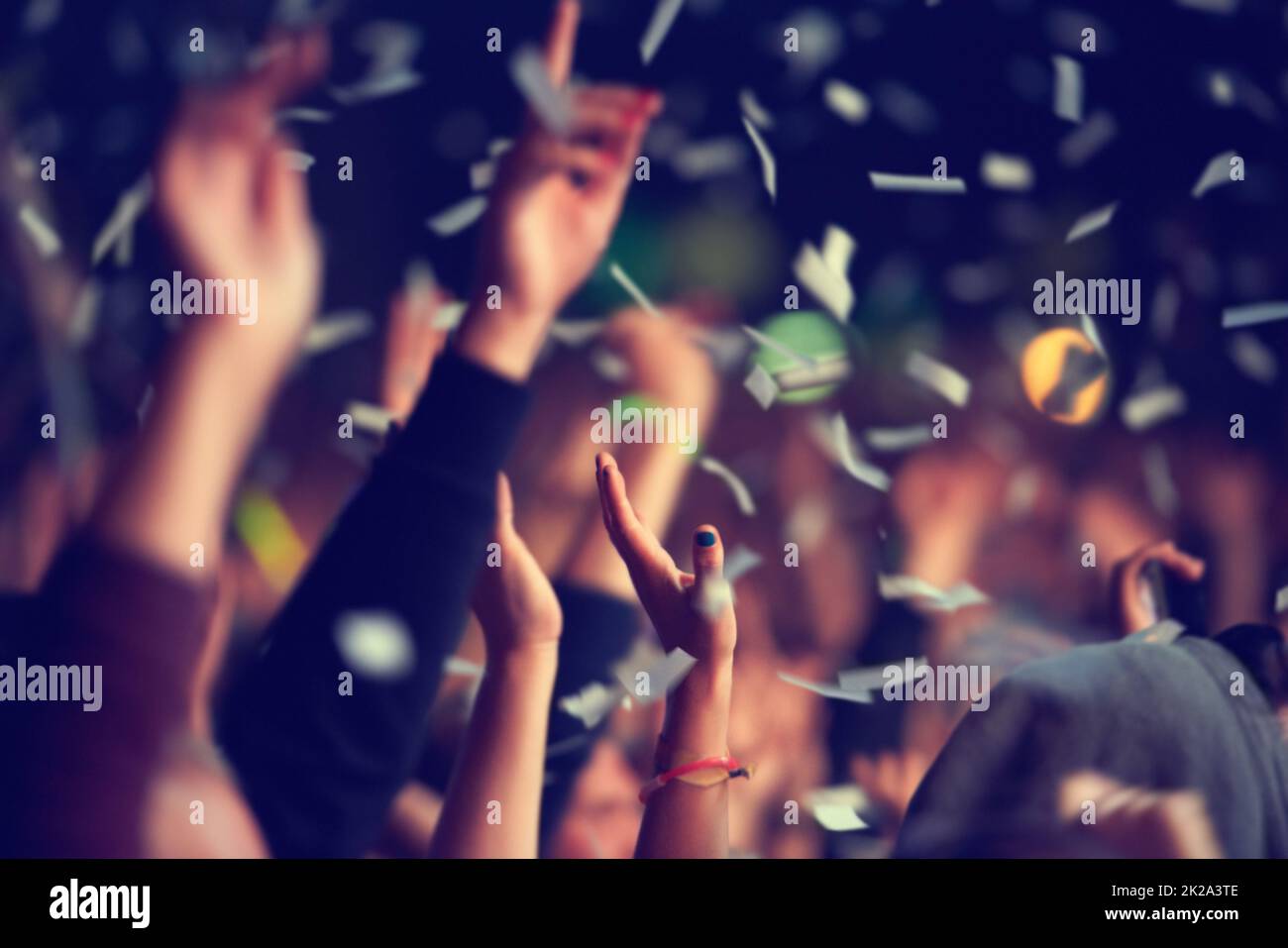 Wild and free. A music festival audience throwing confetti into the air
