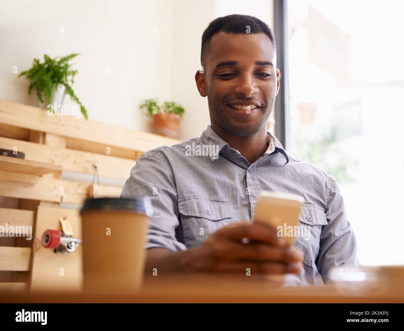 Coffee and wireless freedom. Cropped shot of a young african man using his smartphone in a