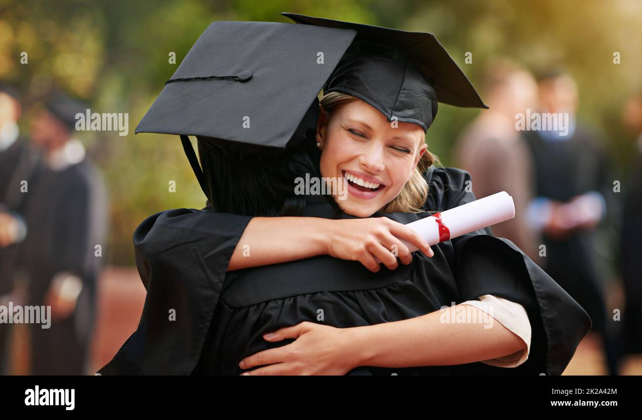 We are finally here. Two college graduates hugging one another in congratulations. Stock Photo