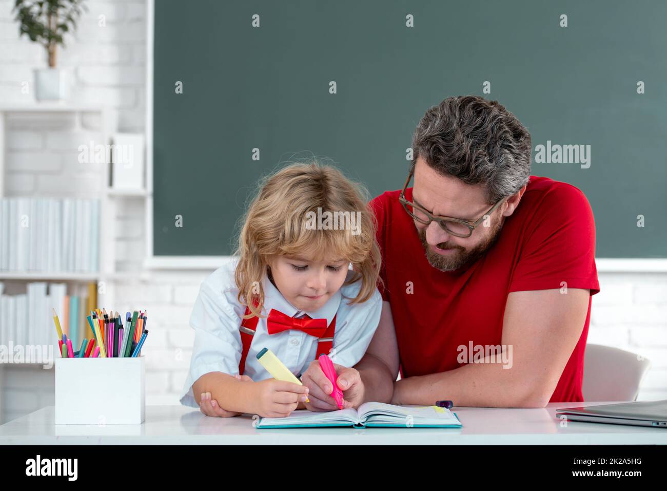Pupil kid student and teacher tutor in classroom at school lesson. Teacher and little student portrait, teachers day. Stock Photo