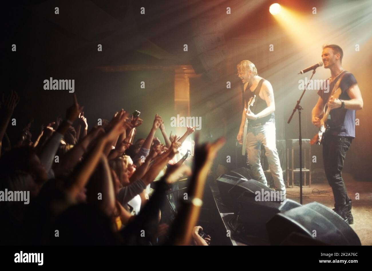 Shot of a crowd of music fans reaching up at a guitarist on stage. This concert was created for the sole purpose of this photo shoot, featuring 300 models and 3 live bands. All people in this shoot are model released. Stock Photo