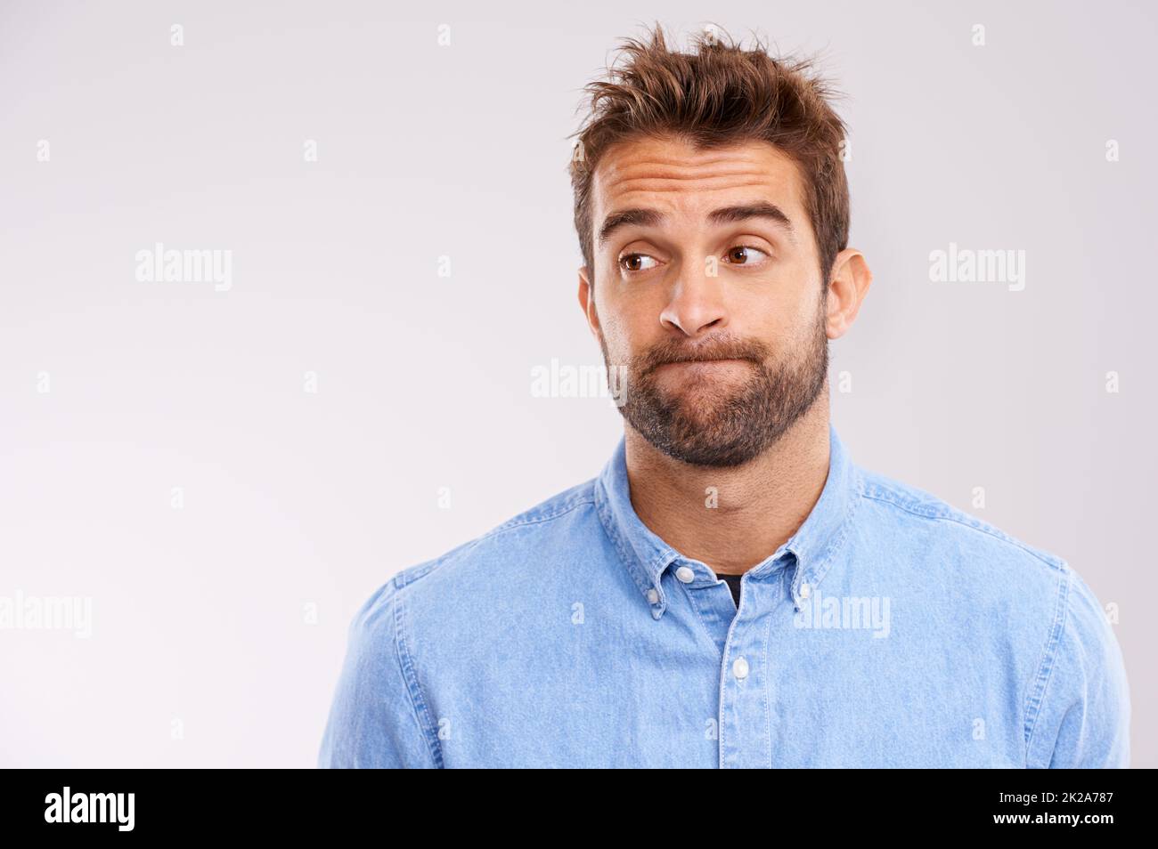 Uhhhmm.... A studio shot of a handsome man making a face. Stock Photo