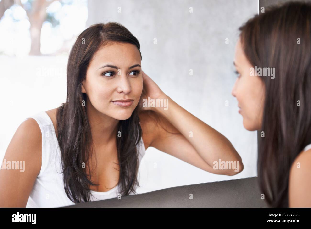 Getting excited for her date. A cropped shot of a beautiful young woman deciding on a hair style in front of her bathroom mirror. Stock Photo